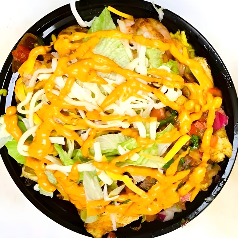A close-up of a vibrant salad bowl with lettuce, cheese, and orange dressing.