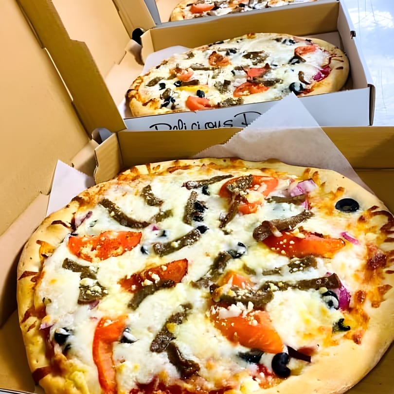 Three Pizza Brothers pizzas in open boxes, topped with white cheese, tomatoes, olives, and meat.